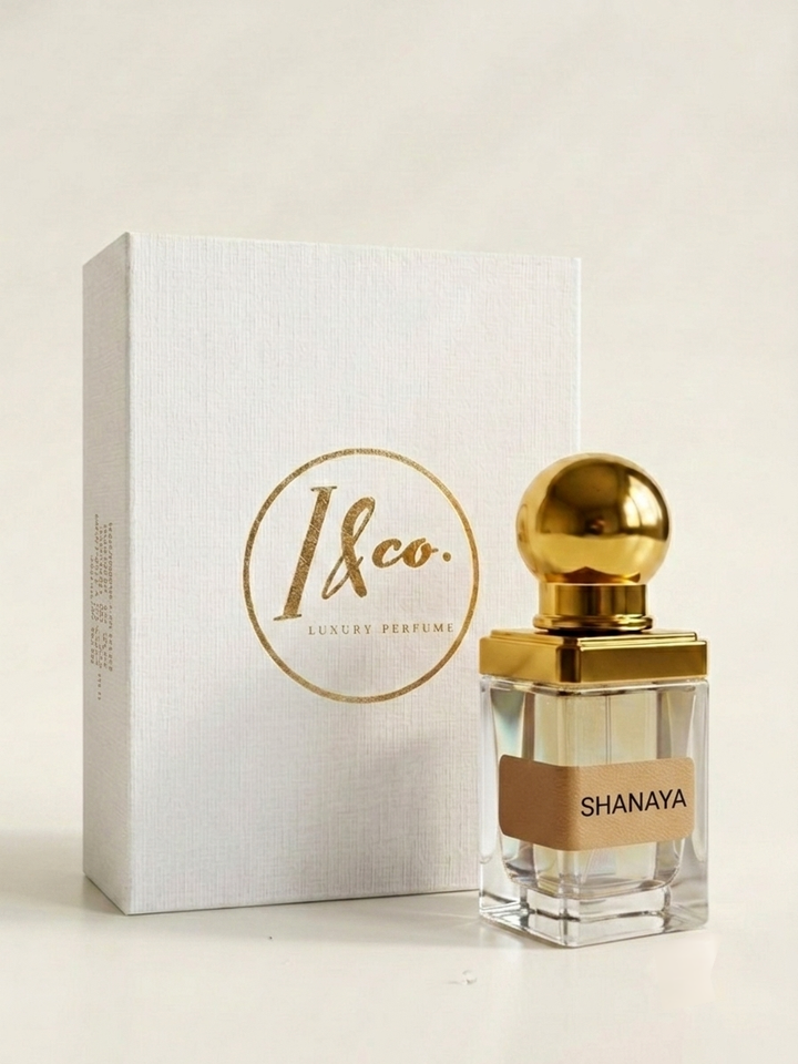 Shanaya perfume bottle with a gold cap next to its white and gold 1&co. box, on a light beige background.